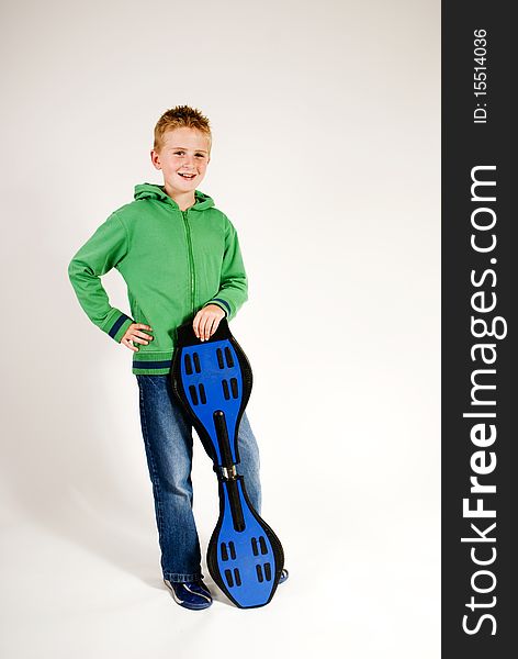 A vertical image isolated against a plain background,teenage boy standin leaning on waveboard,blonde hair,green top blue jeans,smiling. A vertical image isolated against a plain background,teenage boy standin leaning on waveboard,blonde hair,green top blue jeans,smiling