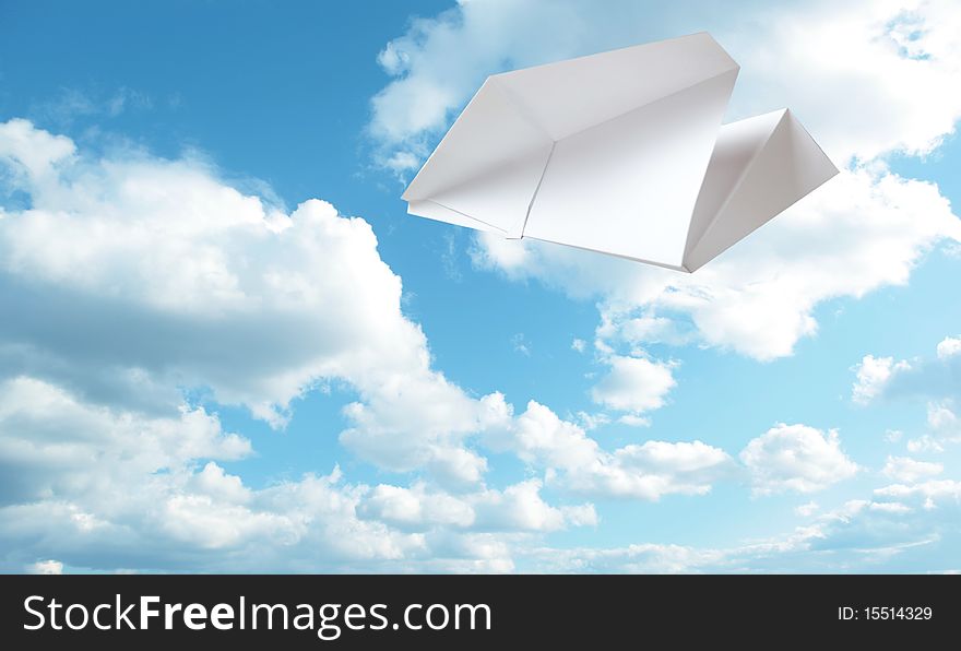 White  paper plane flying. Sky and clouds in the background