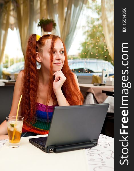 Girl with a cocktail and the laptop in cafe. Girl with a cocktail and the laptop in cafe