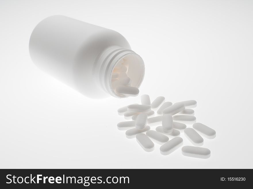 Prescription medicine pills pouring out of white bottle on white background. Prescription medicine pills pouring out of white bottle on white background