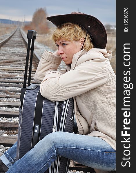 Respite on the railroad tracks, a woman pilgrim from the suitcase sitting in the image of the cowboy. Respite on the railroad tracks, a woman pilgrim from the suitcase sitting in the image of the cowboy