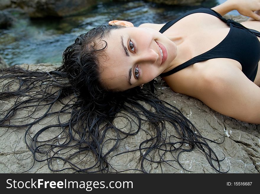 Pretty girl  lying  on the rock at the sea