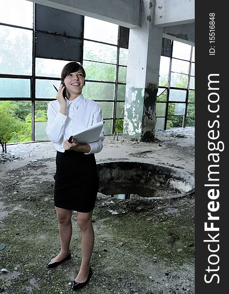 Young business woman talking on mobile phone about demolished building. Young business woman talking on mobile phone about demolished building