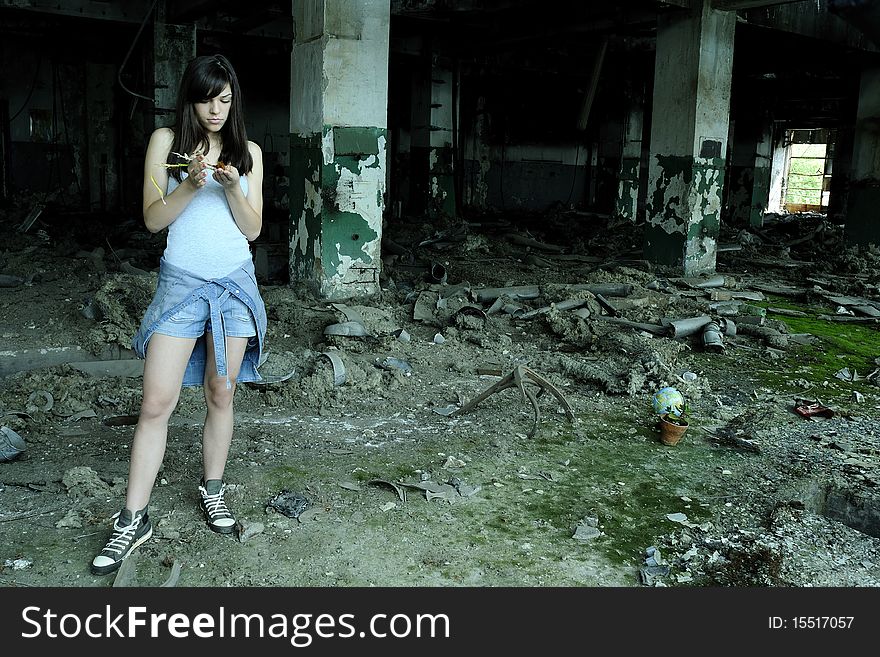 Caucasian young woman studying plant in devastated building. Caucasian young woman studying plant in devastated building