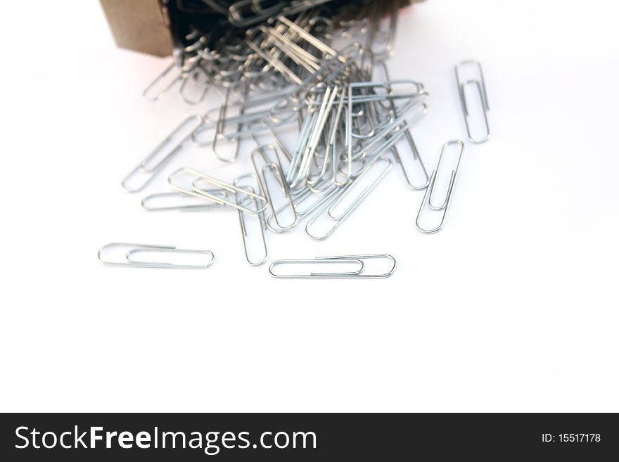 Box of paper clips spilled over white background