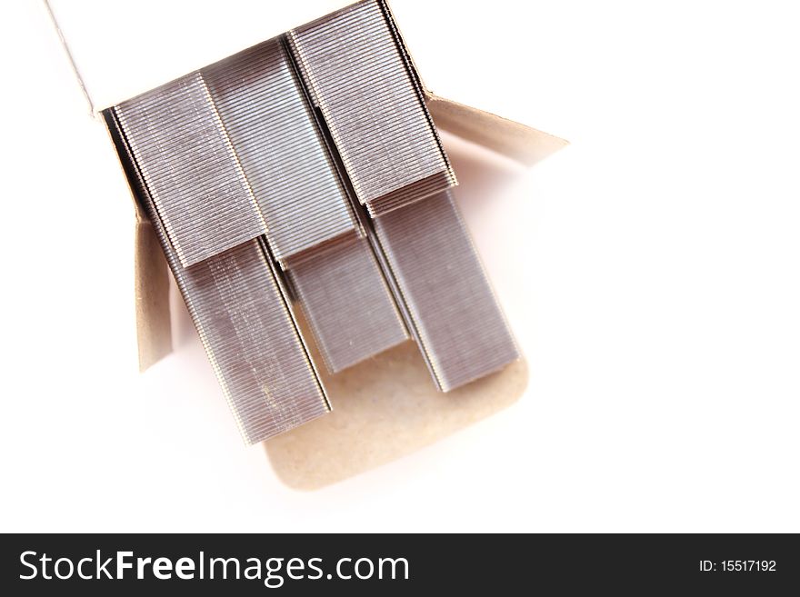 Open box of silver metal staples over white backgound)