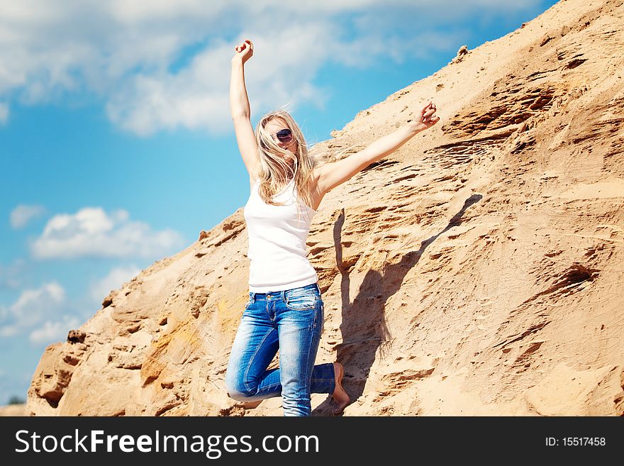 Young girl the blonde in jeans, against sand