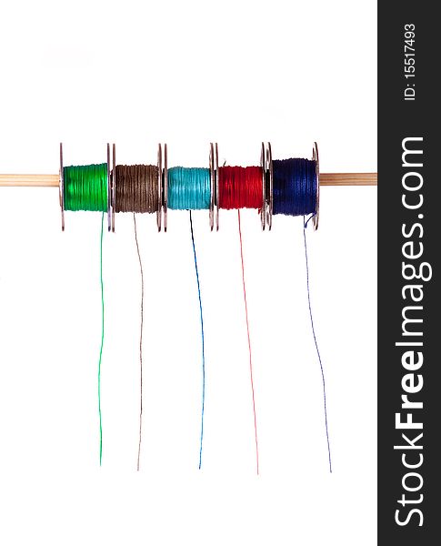 A row of five coloured cotton bobbins against a white background. A row of five coloured cotton bobbins against a white background
