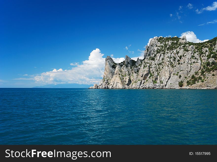 The pointed cape juts far into the Black Sea. It is photographed from the dark blue sea. The pointed cape juts far into the Black Sea. It is photographed from the dark blue sea.