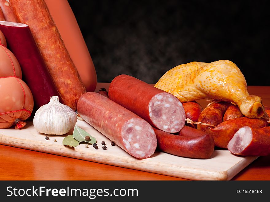 A variety of processed cold meat products, on a wooden cutting board. A variety of processed cold meat products, on a wooden cutting board.