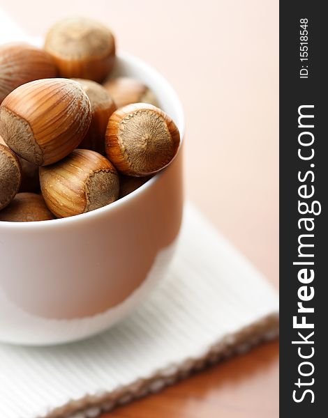 Hazelnuts in a cup on wooden table