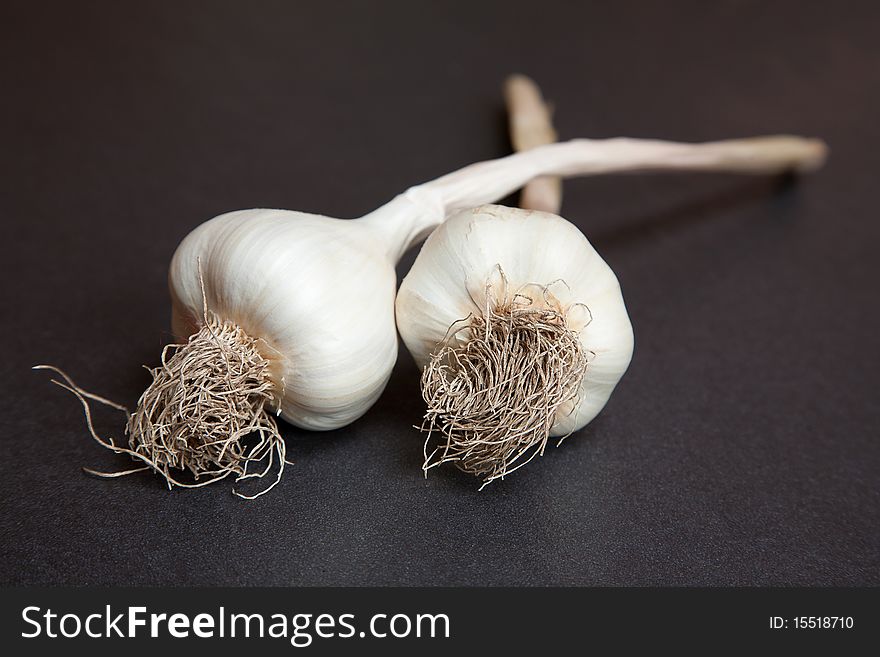 Two organic garlic bulbs on a grey worktop. Two organic garlic bulbs on a grey worktop.