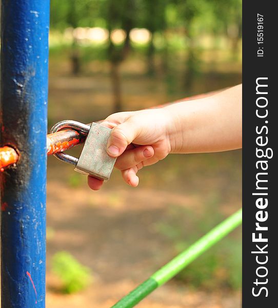 Child's hand touched the closed lock on the lattice