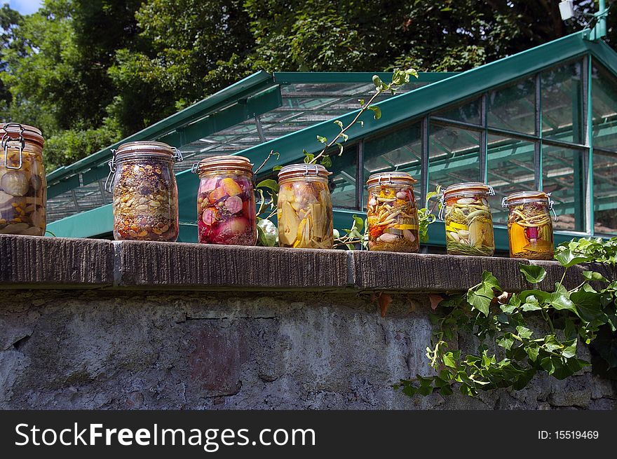 Jars of tinned vegetables aligned on a wall of the kitchen garden. Jars of tinned vegetables aligned on a wall of the kitchen garden.