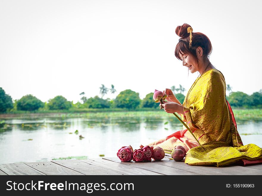 A beautiful woman wearing an ancient Thai dress is folding a lotus flower to offer the Buddha. A beautiful woman wearing an ancient Thai dress is folding a lotus flower to offer the Buddha