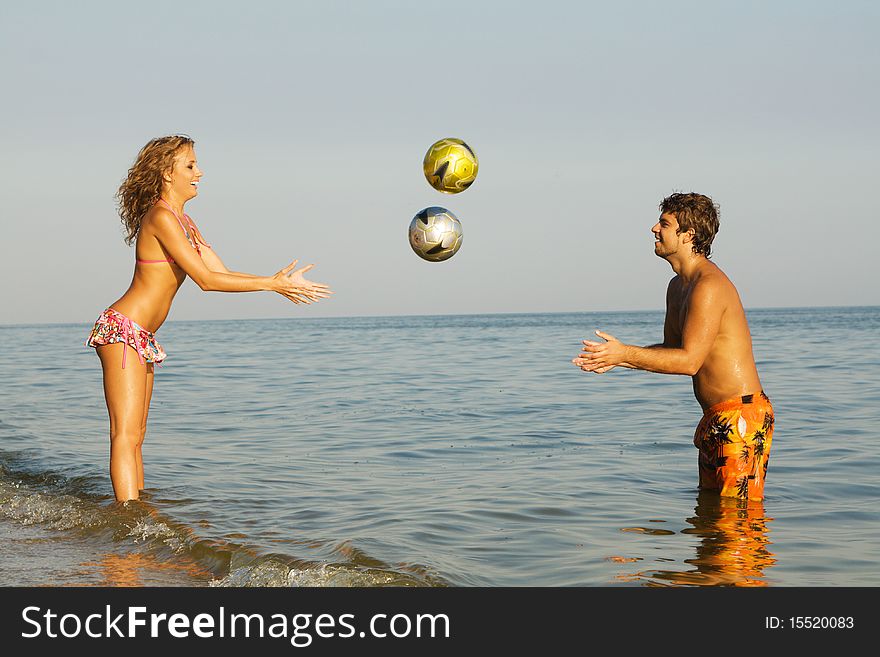 Funny young couple playing balls on the beach. Funny young couple playing balls on the beach