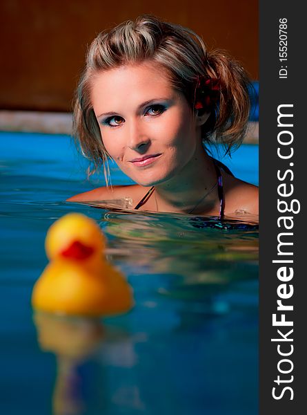 Young girl in pool with yellow duck in front of her. Young girl in pool with yellow duck in front of her