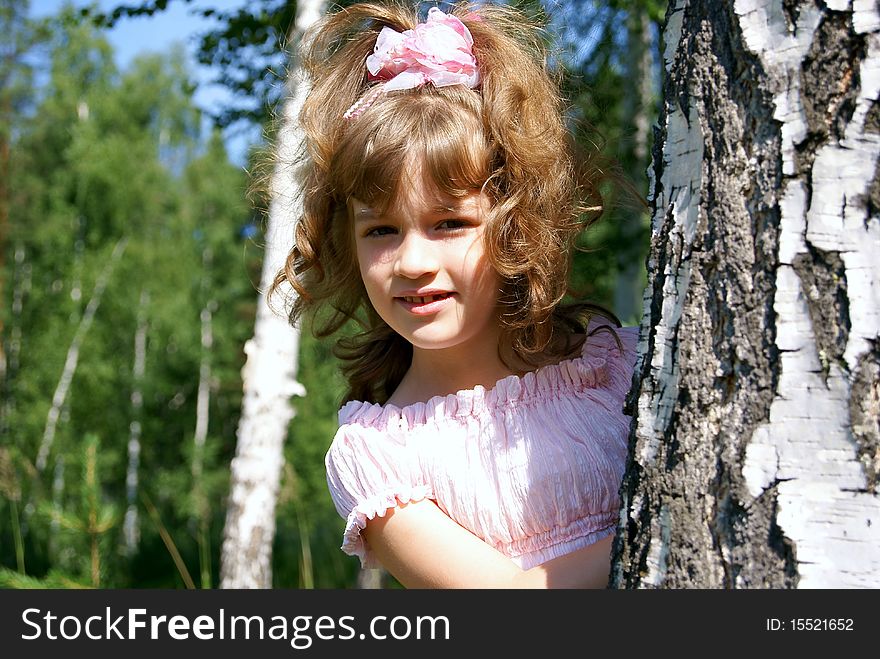 In the summer in park the child looks out because of a tree. In the summer in park the child looks out because of a tree