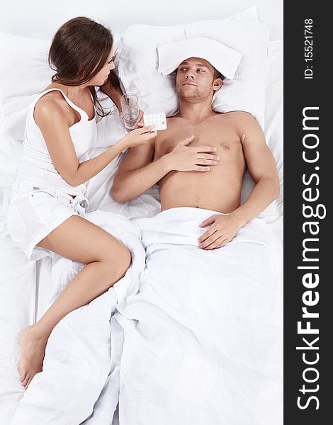 Attractive girl gives tablets sick man in bed. Attractive girl gives tablets sick man in bed