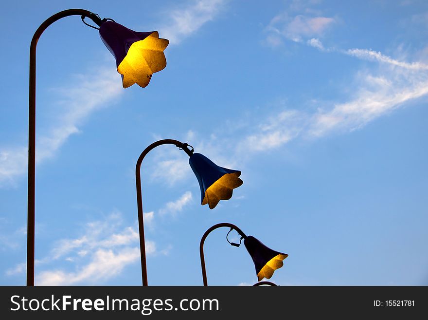 Many antique lamp posts in a row against blue sky. Many antique lamp posts in a row against blue sky