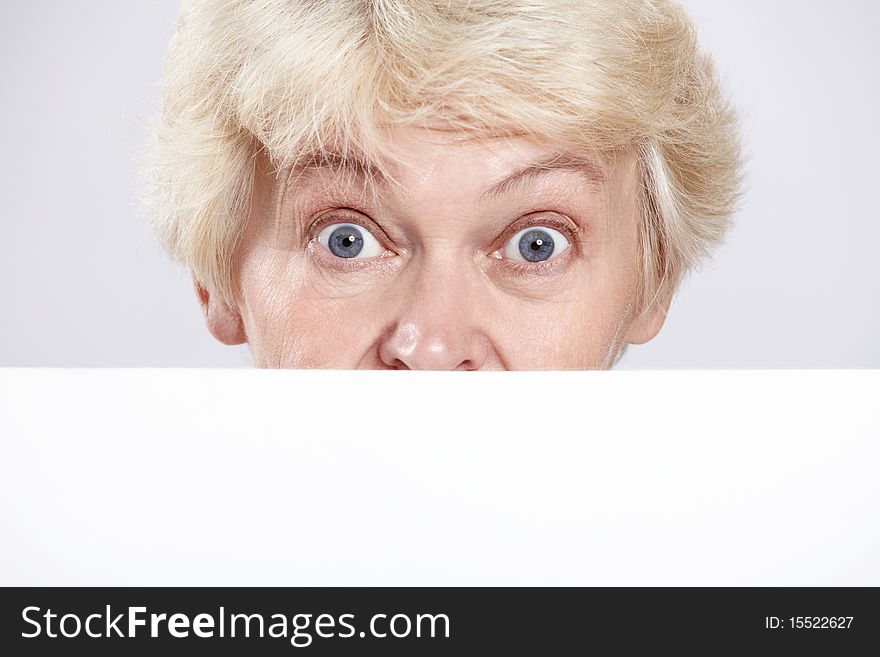 Mature woman with surprised eyes with a blank form closeup. Mature woman with surprised eyes with a blank form closeup