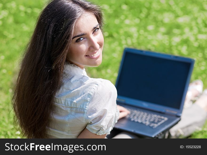 Beautiful young woman with notebook on grass