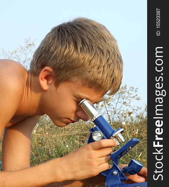 Boy looks through a microscope at the field. Boy looks through a microscope at the field