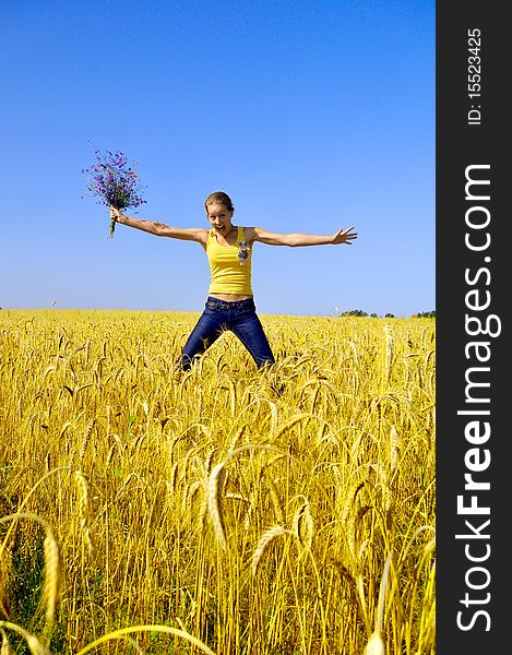 Beautiful smiling girl jumps in the golden field