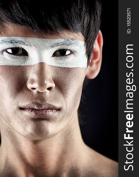 Shot of a stylish young man with painted eyes posing over black background. Shot of a stylish young man with painted eyes posing over black background.