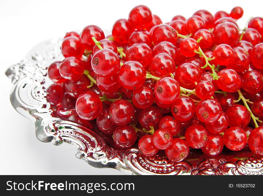 Redcurrants on a silver platter isolated on white background