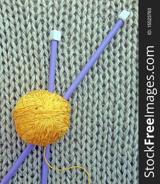 Needles and a ball of yarn lying on woolen knitted cloth. Needles and a ball of yarn lying on woolen knitted cloth