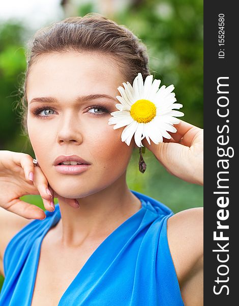 Attractive young lady holding chamomile and looking away. Attractive young lady holding chamomile and looking away