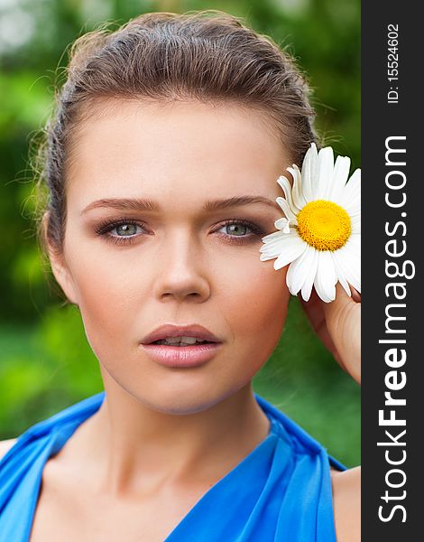 Closeup portrait of attractive caucasian woman holding chamomile near her face and looking at camera. Closeup portrait of attractive caucasian woman holding chamomile near her face and looking at camera