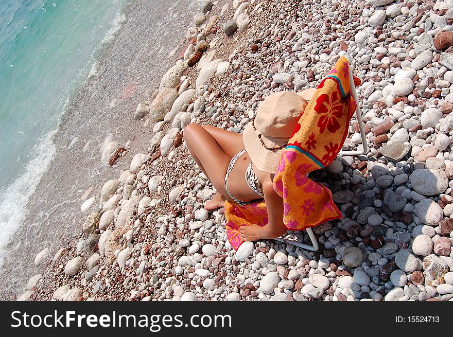 A girl sitting on a sunbed on Adriatic beach in Montenegro. A girl sitting on a sunbed on Adriatic beach in Montenegro