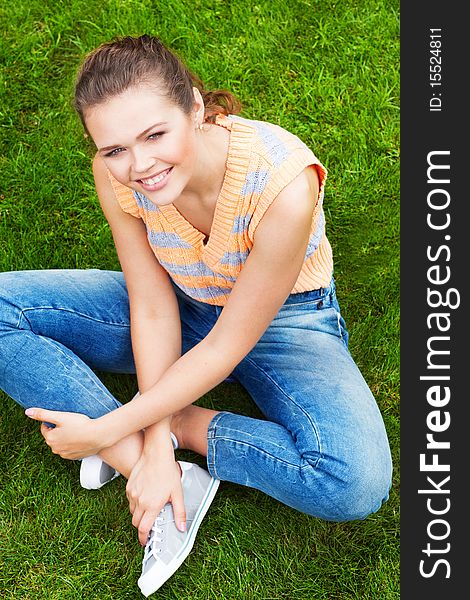 Beautiful caucasian girl wearing casual clothes sitting on grass and looking at camera. Beautiful caucasian girl wearing casual clothes sitting on grass and looking at camera