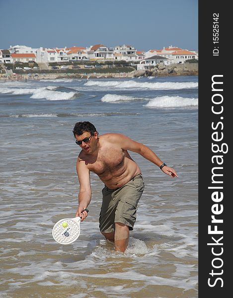 A fat man playing beach tennis on the beach