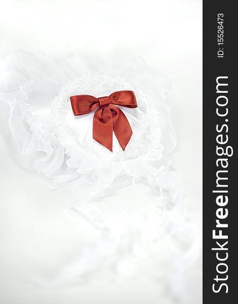 A White wedding veil encircling a red bow on a heart shaped ring pillow with white background and a Title Space on the Top Portion. A White wedding veil encircling a red bow on a heart shaped ring pillow with white background and a Title Space on the Top Portion.