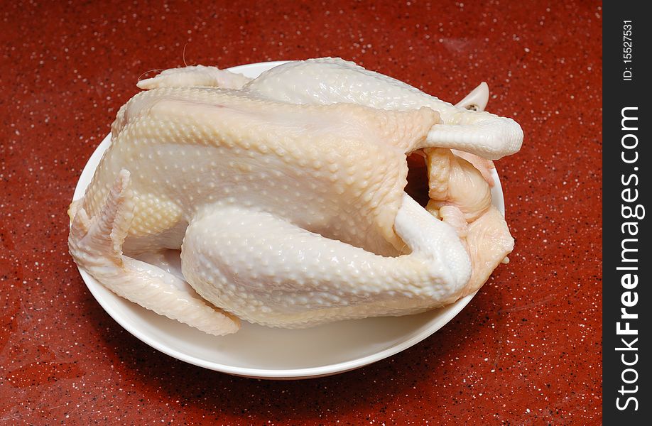 Uncooked chicken put in the white dish.