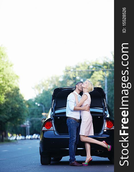 A young couple kissing on the background of auto. A young couple kissing on the background of auto