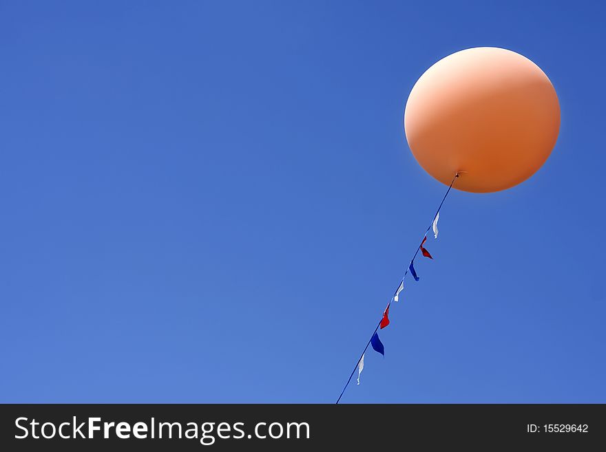 One orange balloon floating in bright blue sky. One orange balloon floating in bright blue sky
