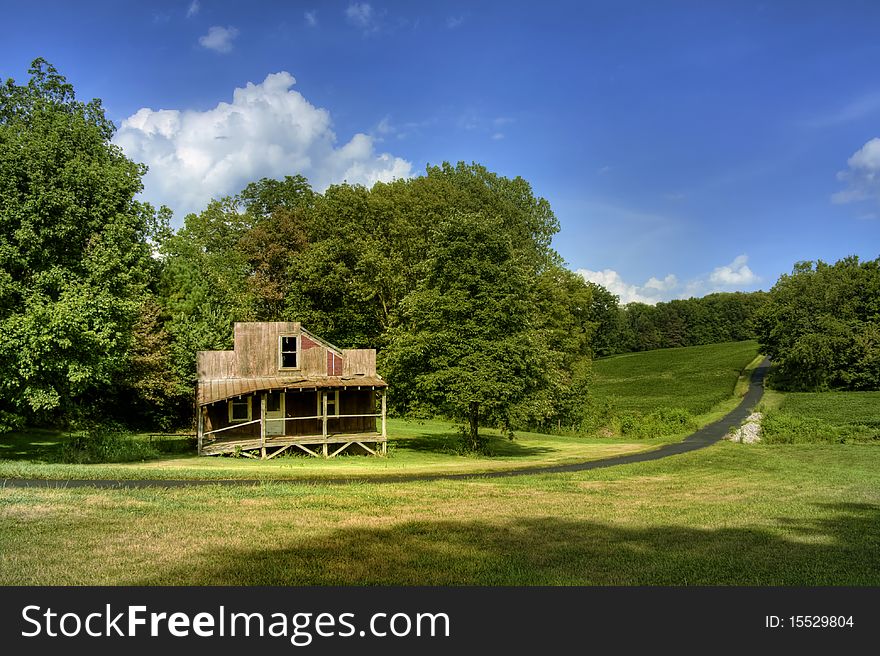 Old abandoned rustic house, green hill and trees, with blue sky and white clouds. Old abandoned rustic house, green hill and trees, with blue sky and white clouds