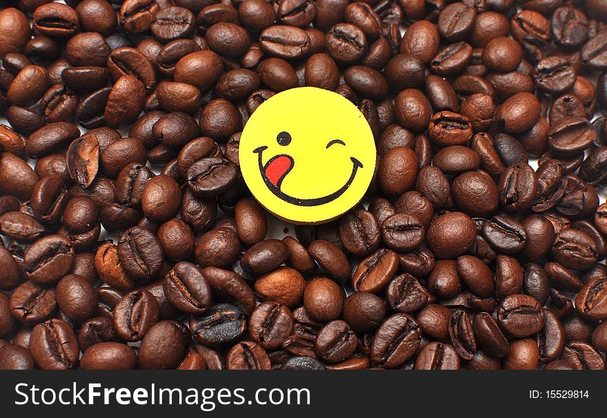 Yellow button is a happy face on the background of the coffee bean. Yellow button is a happy face on the background of the coffee bean