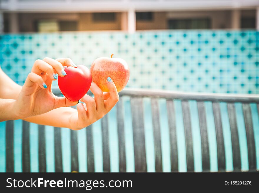 Women hold hearts with apples, eat fruits for good health. Women hold hearts with apples, eat fruits for good health