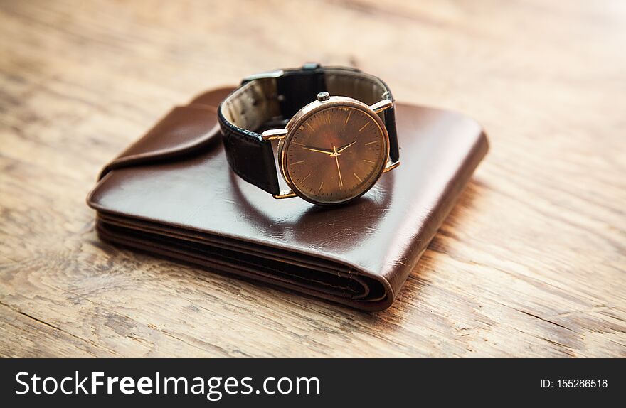 Wristwatch with wallet on wooden background
