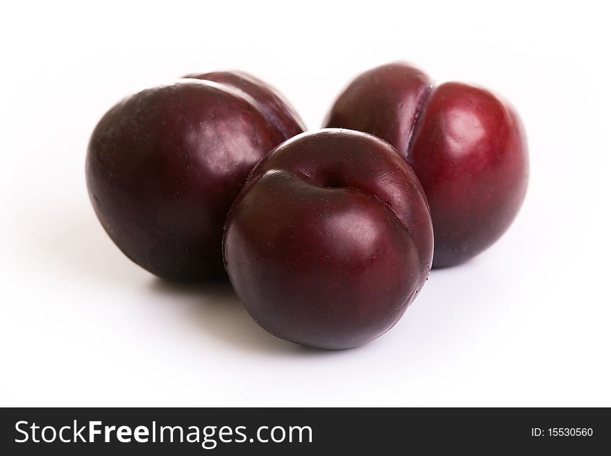 Three juicy red plums on a white background