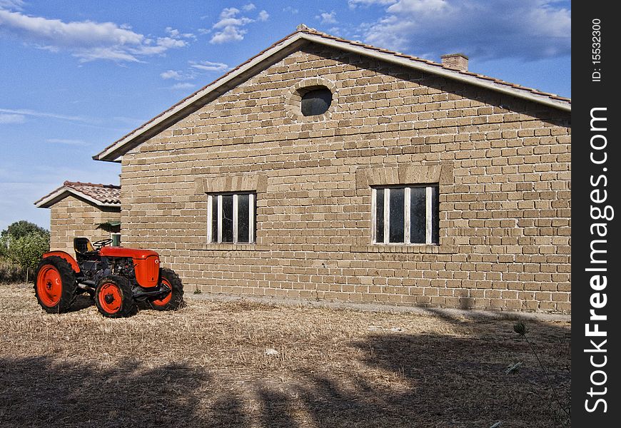 Red tractor parked in front of an empty farm. Red tractor parked in front of an empty farm