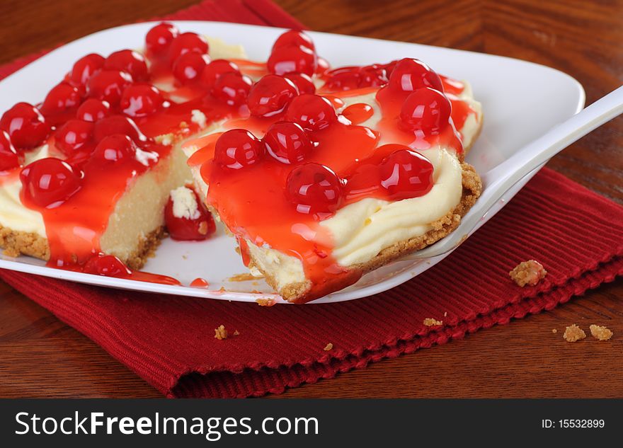 Closeup of a cheesecake topped with cherries with a slice on a spatula. Closeup of a cheesecake topped with cherries with a slice on a spatula