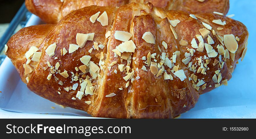 Horizontal close-up photo of fresh baked croissant with sliced almonds. Horizontal close-up photo of fresh baked croissant with sliced almonds