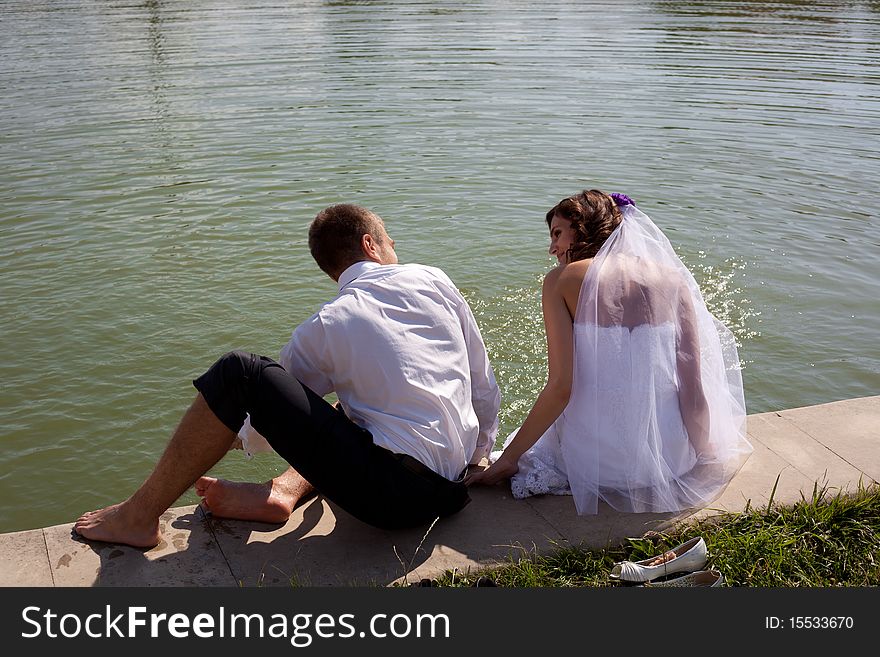 Bride and groom posing with back near water. Bride and groom posing with back near water