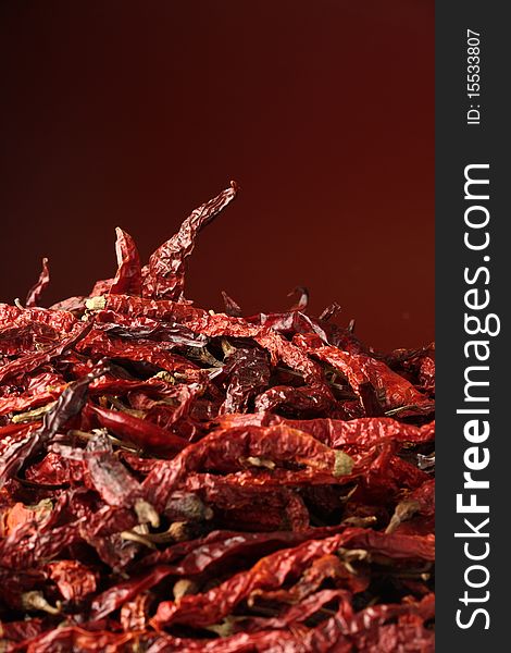 A heap of dried red chillies. Focussed on the top one.
